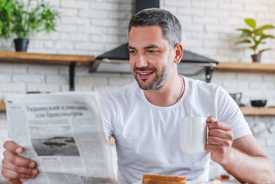 Mann, der beim Frühstück eine Zeitung liest
